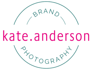 A graphic of a logo against a white background. Pink wording through the middle reads 'Kate Anderson' and a tea; circular line like a stamp incorporates the wording. Within the cicle it reads Brand at the top and Photography beneath.