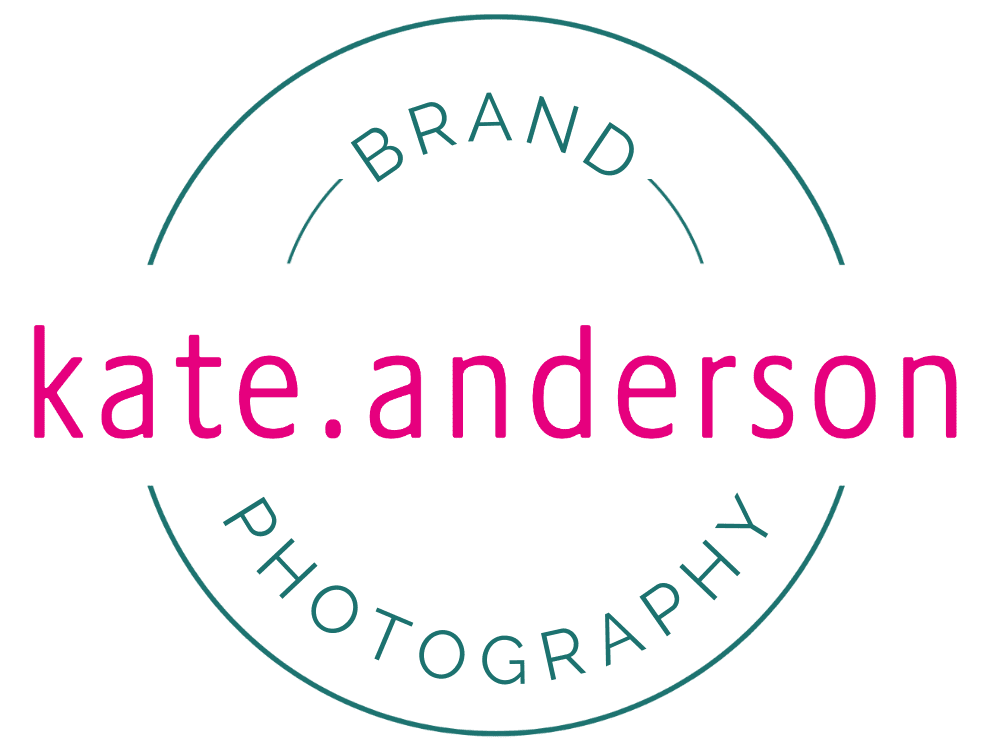 A graphic of a logo against a white background. Pink wording through the middle reads 'Kate Anderson' and a tea; circular line like a stamp incorporates the wording. Within the cicle it reads Brand at the top and Photography beneath.